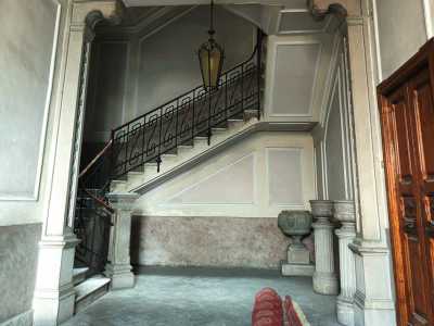 L�ingresso principale conduce in un semplice androne dalle pareti grigie e crema, abbellito da due colonne con fregi vegetali e da un fine lampadario in ferro (foto di Michele Iannone)